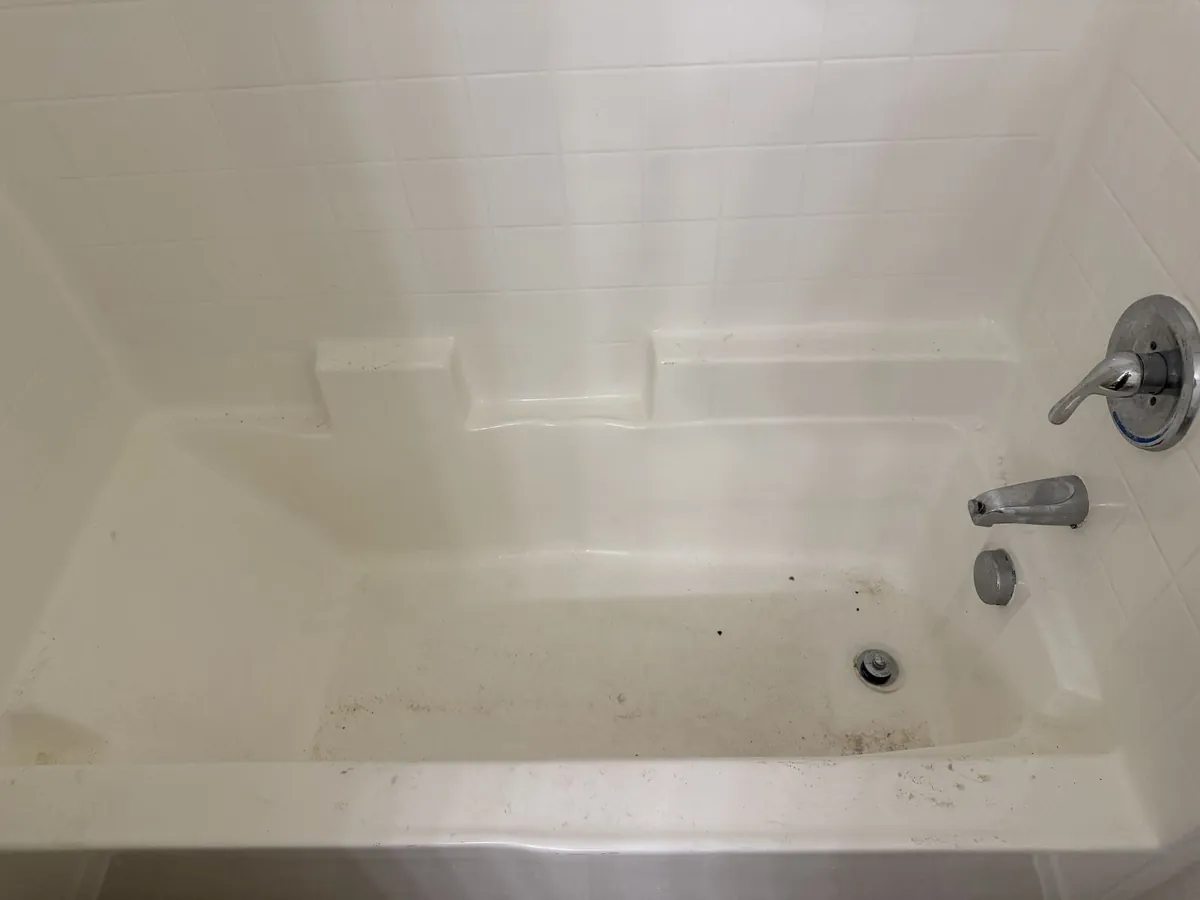 Bathtub before apartment turnover cleaning — stained with residue